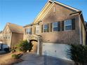 Two-story brick home with a large garage and manicured landscaping at 5150 Amberland Sq, Atlanta, GA 30349
