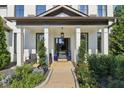 Inviting front porch with columns, lush landscaping, and a stylish door at 334 Spotted Ridge Cir, Woodstock, GA 30188