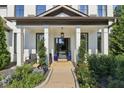 Charming front porch featuring classic columns, neat landscaping and an inviting black front door at 334 Spotted Ridge Cir, Woodstock, GA 30188