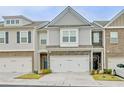 Townhome exterior featuring stone accents and a two-car garage at 7628 Squire Ct, Fairburn, GA 30213