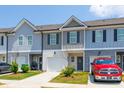 Two story townhouses with gray siding, white garage doors, landscaping, and red truck parked at 7144 Gladstone Cir, Stonecrest, GA 30038