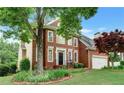 Beautifully landscaped front yard highlights this classic brick home with mature trees and attached two-car garage at 205 Glenbrook Ln, Canton, GA 30115