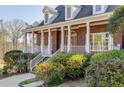 Charming brick home featuring a welcoming front porch with white pillars and lush landscaping at 1630 Bettis Tribble Gap Rd, Cumming, GA 30040