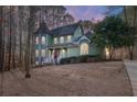 Exterior view of a charming two-story green house at dusk at 7825 Brands Hatch Blvd, Cumming, GA 30040