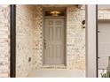 Elegant front door with a classic design, complemented by brick accents and a modern light fixture, creating a welcoming entrance at 7289 Eton Ln, Locust Grove, GA 30248