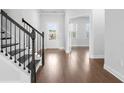 Inviting foyer featuring wood flooring, a staircase with black iron railings, and a front door at 1646 Tide Mill Rd, Cumming, GA 30040