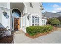 Elegant entrance with arched entryway, wood door, and landscaping at 2870 The Terraces Way, Dacula, GA 30019