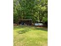 Backyard with wood pile, propane tank, and lush greenery at 3639 Holly Springs Rd, Rockmart, GA 30153