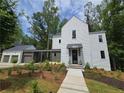 Modern white two-story home features a connected garage, a covered entrance, and fresh landscaping at 135 Cedarwood Ln, Roswell, GA 30075