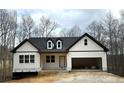 New construction home with board and batten siding, black trim, a two-car garage, and a welcoming front porch at 319 Evie Ln, Canton, GA 30115