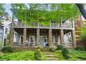 Two story home with stone porch supports, an open porch on the second story, and a manicured front yard at 9032 Selborne Ln, Chattahoochee Hills, GA 30268