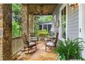 Relaxing covered porch featuring stone flooring, comfortable seating, and a ceiling fan at 9032 Selborne Ln, Chattahoochee Hills, GA 30268