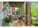 Inviting covered porch with stone pillars, ceiling fan, and comfortable seating area at 9032 Selborne Ln, Chattahoochee Hills, GA 30268