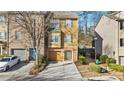 Tan three-story townhome with a brick facade, attached garage, and landscaping at 2793 Keystone Ave, Lithonia, GA 30058