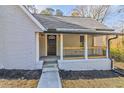 A welcoming front porch featuring black trim, brick accents, a black front door, and wooden porch railing at 204 Elm St, Palmetto, GA 30268