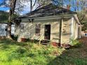 Back of the house showing boarded windows and overgrown yard at 309 Holderness Sw St, Atlanta, GA 30310