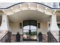 Elegant front entrance with a covered porch, stone pillars, and a modern glass door at 923 Little Darby Ln, Suwanee, GA 30024