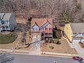 Aerial view of a two-story home with a brick facade, red shutters, front porch, two car garage, and mature trees at 753 Win West Xing, Auburn, GA 30011