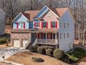 Charming two-story home with a brick facade, red shutters, front porch, two car garage, and manicured landscaping at 753 Win West Xing, Auburn, GA 30011