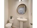 Small, updated powder room with pedestal sink and a round mirror at 591 River Gardens Se Dr, Atlanta, GA 30354