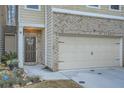 Townhome featuring an attached garage, brick accents, and a welcoming front door at 1766 Orange Grove Pl, Austell, GA 30106
