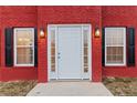 White front door flanked by windows with black shutters on a red brick house at 1029 Chaterly Ct, Riverdale, GA 30296