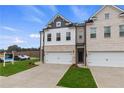 Two-story townhome with brick and gray siding, two-car garage, and landscaping at 8194 Tiger Way, Riverdale, GA 30274