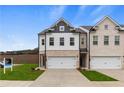 Two story townhome with white and brick exterior, two car garage, and landscaping at 8218 Tiger Way, Riverdale, GA 30296