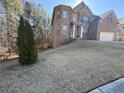 Two-story house on a sloped lot with mature trees nearby at 15 Manas Ct, Covington, GA 30016