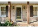 Charming front porch showcasing brick detailing, wooden support beams, and stylish outdoor lighting fixtures at 1354 Drayton Woods Dr, Tucker, GA 30084