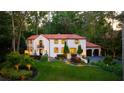 Evening view of charming Spanish-style home with landscape lighting and lush landscaping at 1598 W Sussex Ne Rd, Atlanta, GA 30306