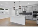 Modern kitchen with a large island, stainless steel appliances, pendant lights, and gray cabinetry at 6210 Misty Hill Ln, Buford, GA 30518
