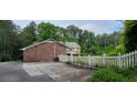 Long driveway with a white picket fence with a well-maintained brick house and lush greenery at 1294 Dogwood Rd, Snellville, GA 30078