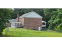 Rear exterior view of a two-story brick home with deck and fenced backyard, surrounded by lush trees at 1294 Dogwood Rd, Snellville, GA 30078