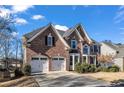 Brick front of a two-story house featuring a three-car garage at 3845 Montvale Xing, Cumming, GA 30041