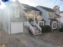 Gray townhome with white garage door and wooden stairs leading to the entrance at 390 Lakeridge Ct, Riverdale, GA 30274