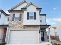 Two-story townhome with stone and white siding, two-car garage, and landscaping at 1394 Ben Park Way, Grayson, GA 30017