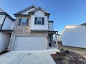 Two-story townhome with stone and white siding, two-car garage, and landscaping at 1394 Ben Park Way, Grayson, GA 30017