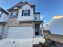 Two-story townhome with stone and white siding, two-car garage, and landscaping at 1394 Ben Park Way, Grayson, GA 30017