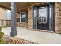 Covered front porch with brick columns and a black front door at 654 Ocean Ave, Canton, GA 30114