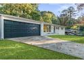 Newly renovated home with a dark-colored garage door and a spacious driveway at 1921 Westwood Sw Ave, Atlanta, GA 30310