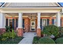 Inviting front porch with brick columns, a welcoming wreath, and lovely landscaping, perfect for relaxing at 535 Cape Ivey Dr, Dacula, GA 30019