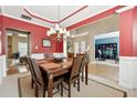 Formal dining room with red walls, wood flooring, and a chandelier at 724 Landsdowne Ln, Locust Grove, GA 30248