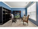 Bright home office with blue walls, built-in shelving, and two wicker chairs at 724 Landsdowne Ln, Locust Grove, GA 30248