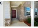 Close up of the front door with brick accents, gray shutters, and lush green bushes at 816 Royal Red Ct, Mcdonough, GA 30253