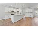 Modern kitchen featuring white cabinets, a center island, stainless steel appliances, and wood flooring at 313 Foxglove Way, Mcdonough, GA 30253