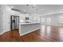 Open-concept kitchen with stainless steel appliances, a large island, white cabinets, and hardwood floors at 236 Begonia Way, Mcdonough, GA 30253