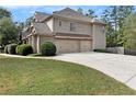 View of the three-car garage with long driveway and well-kept lawn at 5669 Hollowbrooke Nw Ln, Acworth, GA 30101