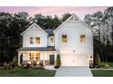 Charming two-story white farmhouse with a covered front porch, landscaped yard, and an attached two-car garage at 319 Willam Gossett Dr, Canton, GA 30114