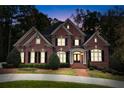 Brick house with black shutters, a large front yard, and a circular driveway at night at 2214 Taylor Grady Ter, Duluth, GA 30097